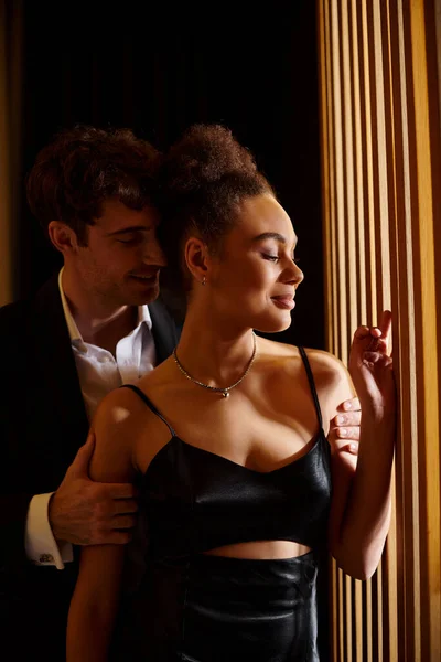 Handsome man in formal wear seducing pleased and beautiful african american woman in black dress — Stock Photo