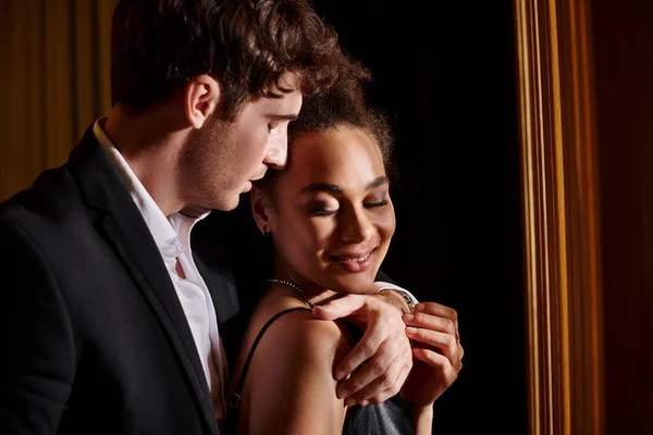 Handsome man embracing cheerful young african american woman during date, love and romance — Stock Photo