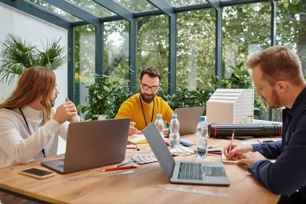 Fröhliche, gut aussehende Geschäftsleute in legerer Kleidung, die gemeinsam aufmerksam an ihrem Start-up arbeiten — Stock Photo