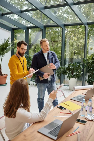 Arquitectos concentrados discutiendo su puesta en marcha y comprobando plantillas y borradores, concepto de negocio - foto de stock