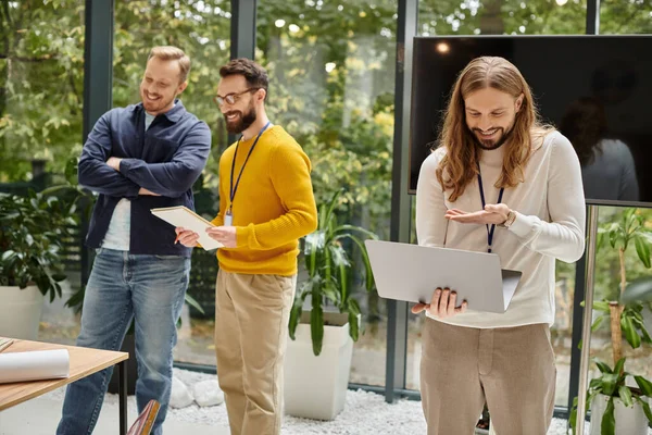 Focus on joyful man in casual attire having videocall and his blurred colleagues discussing startup — Stock Photo