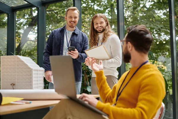 Focus on bearded man talking while on videocall and his blurred jolly colleagues discussing startup — Stock Photo