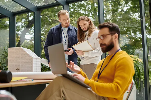Focus on handsome architects discussing project while their blurred colleague having videocall — Stock Photo