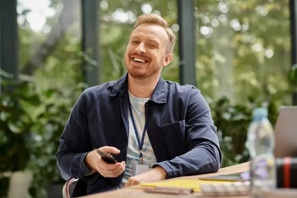 Jolly handsome man in everyday attire sitting at desk and working on his startup while in office — Stock Photo