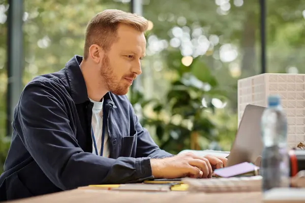 Bell'uomo concentrato in abito casual che lavora alla sua startup con il suo computer portatile in ufficio — Foto stock