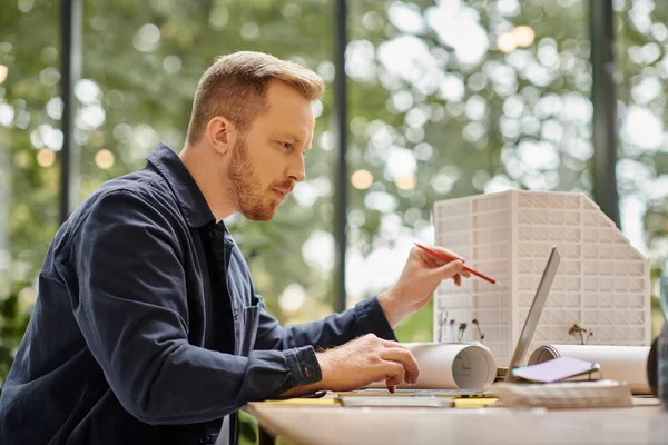 Gutaussehender, konzentrierter Mann in Freizeitkleidung, der mit seinem Laptop im Büro an seinem Start-up arbeitet — Stockfoto