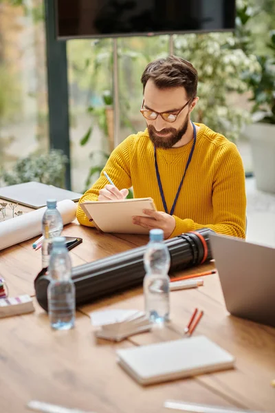Enfocado hombre guapo en cuello alto amarillo casual trabajando en su startup mientras estaba en la oficina - foto de stock