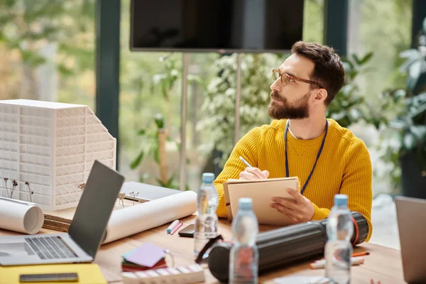 Concentrado atraente homem no casual amarelo gola alta trabalhando em sua startup enquanto no escritório — Fotografia de Stock