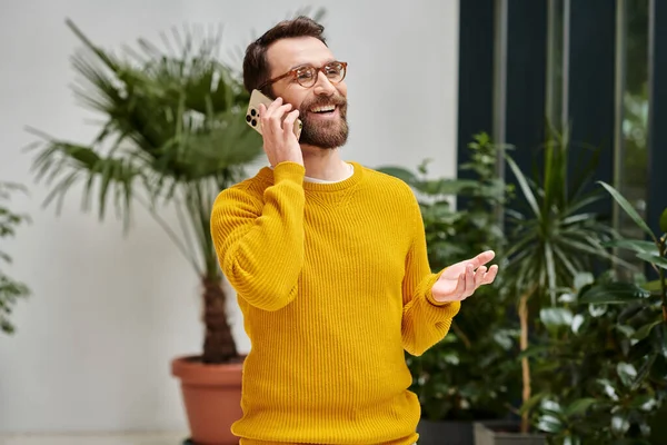 Allegro bell'architetto con occhiali in dolcevita giallo che parla al telefono nel suo ufficio — Foto stock