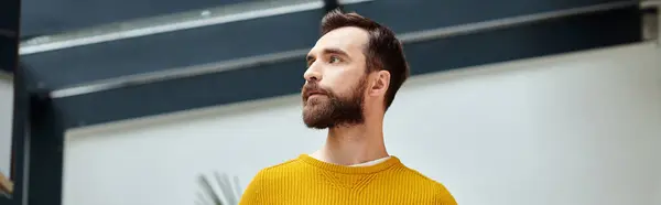 Concentré beau homme barbu à col roulé jaune posant et regardant loin dans le bureau, bannière — Photo de stock