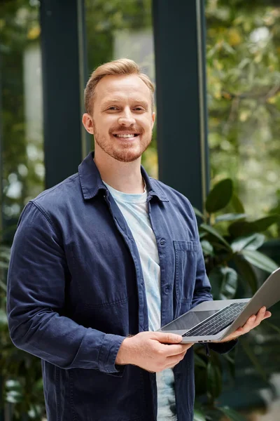Joyous good looking architect in everyday clothes holding his laptop and working on his startup — Stock Photo
