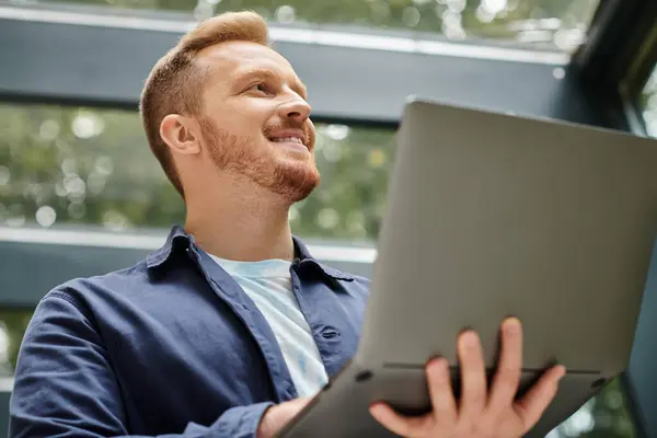 Joyful good looking architect in everyday clothes holding his laptop and working on his startup — Stock Photo