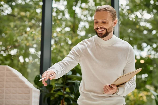 Alegre bonito homem em branco casual gola alta com barba posando em seu escritório enquanto trabalhava duro — Fotografia de Stock