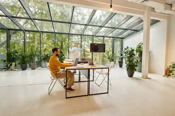 Focus on handsome bearded man working on his laptop while his colleagues posing in blurred motion — Stock Photo