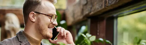 Jolly handsome man with glasses in sophisticated jacket smiling happily and talking by phone, banner — Stock Photo