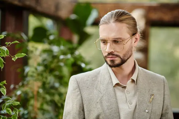 Gut aussehender eleganter Mann mit gesammelten Haaren in Brille im schicken modischen Anzug posiert attraktiv — Stockfoto