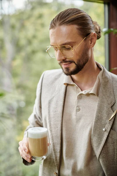 Atraente homem atraente com barba e cabelo coletado em terno elegante beber seu café quente — Fotografia de Stock