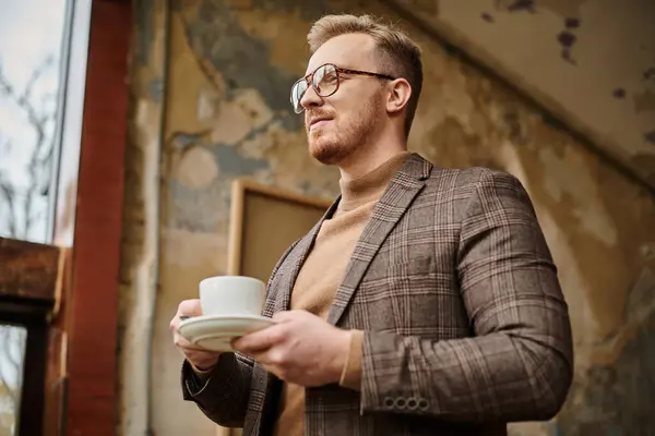 Fröhlicher, kultivierter Geschäftsmann mit Brille im eleganten Anzug, der seinen heißen Kaffee trinkt — Stockfoto