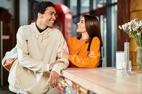 Счастливые чернокожие мужчина и женщина наслаждаются разговором, стоя у стойки администратора в хостеле — стоковое фото