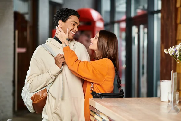 Cariñosa pareja diversa compartiendo un momento tierno, con la mujer tocando la cara del novio - foto de stock