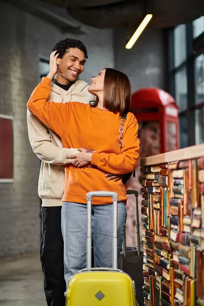 Donna felice abbracciando il suo ragazzo nero vicino alla reception in ostello, coppia di viaggio — Foto stock