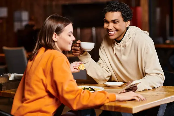 Разнообразная пара делится теплой беседой за чашечкой кофе, черный мужчина смотрит на красивую женщину в кафе — стоковое фото