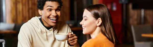 A content man sips his warm coffee as he shares a smile with his stylish girlfriend, banner — Stock Photo