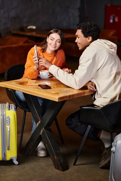 Black man and happy woman using smartphone while sitting at table with coffee in cafe — Stock Photo