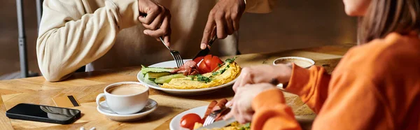 Diverse couple enjoying breakfast with delicious omelette,  and sausages near cups of coffee, banner — Stock Photo