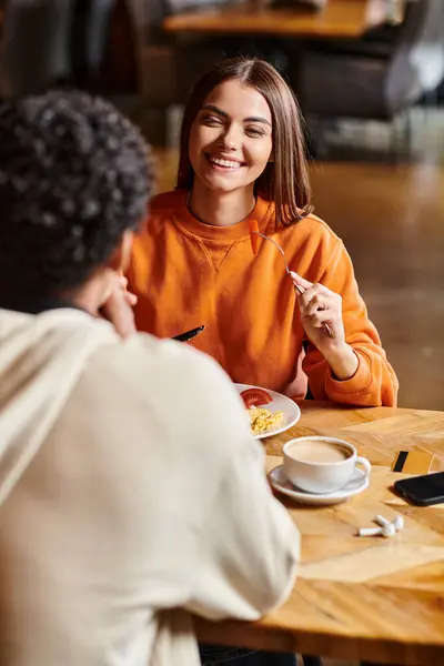 Sorridente giovane donna avendo una piacevole conversazione con il fidanzato per un pasto in un accogliente caffè — Foto stock