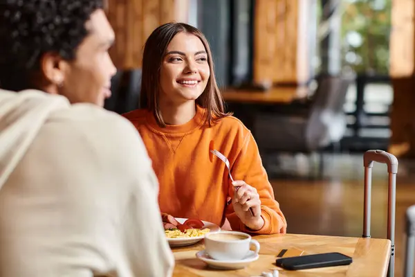 Lächelnde junge Frau beim Frühstück mit Freund in einem gemütlichen Café — Stockfoto