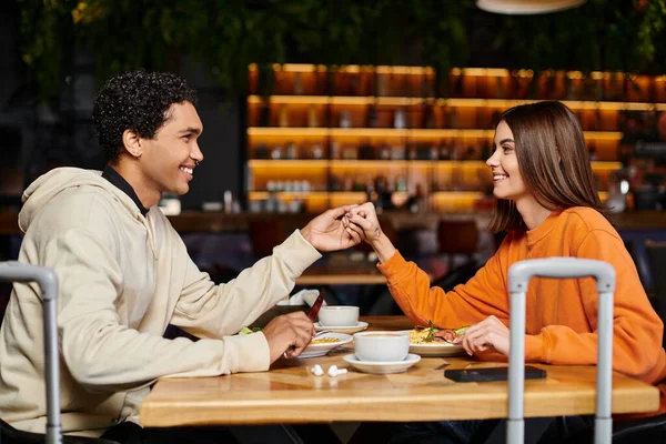 Happy diverse couple enjoying a delicious meal in the charming indoor restaurant, holding hands — Stock Photo