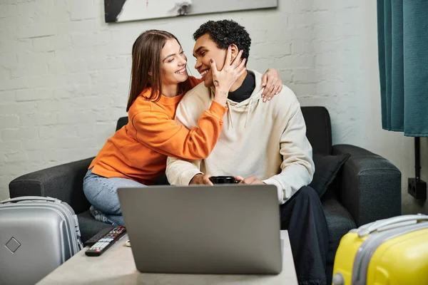 Smiling diverse couple sitting on sofa, woman touching face of black boyfriend — Stock Photo
