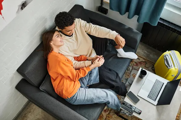 Intime Overhead-Aufnahme eines interrassischen Paares, das auf einem Sofa liegt und sich gemeinsam einen Film auf dem Laptop ansieht — Stockfoto