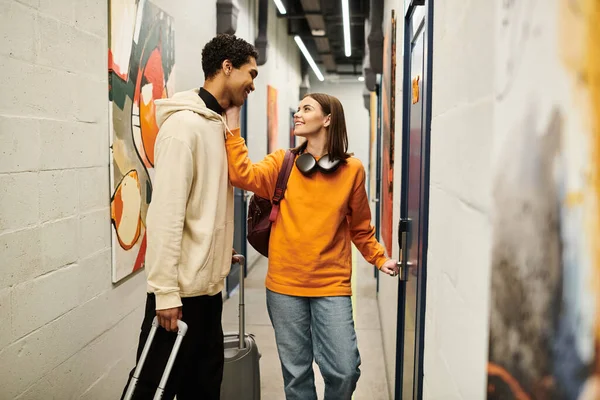Young interracial couple smiling in hostel hallway, cheerful woman opening door to their room — Stock Photo