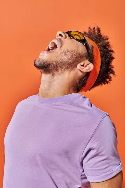 Happy african american fella in eyeglasses laughing out loud on orange background, optimistic man — Stock Photo