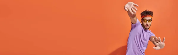 Drôle homme afro-américain en lunettes et bandeau regardant la caméra sur fond orange, bannière — Photo de stock