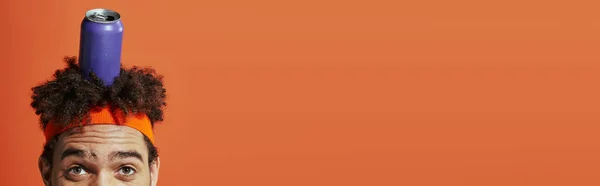 Lattina di soda viola sulla testa dell'uomo riccio africano americano con fascia su sfondo arancione, banner — Foto stock