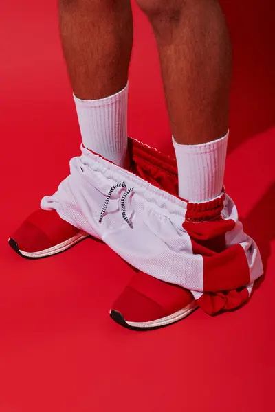 Foto conceptual, hombre recortado en zapatillas de deporte, calcetines blancos y corredores de pie sobre fondo rojo - foto de stock