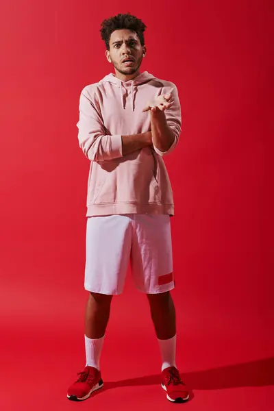 Serious african american sportsman in gym clothes gesturing while complaining on red background — Stock Photo