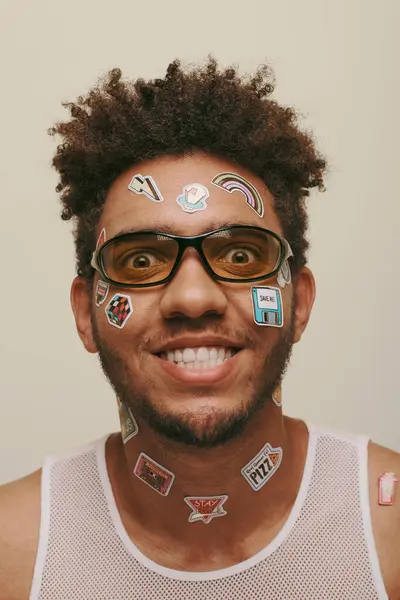 Cheerful african american man in sunglasses with trendy stickers on face on grey background — Stock Photo