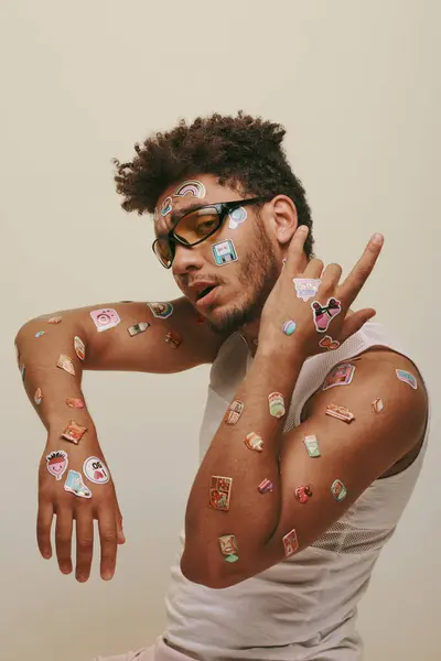 African american guy in sunglasses with stickers on face looking at camera on grey background — Stock Photo