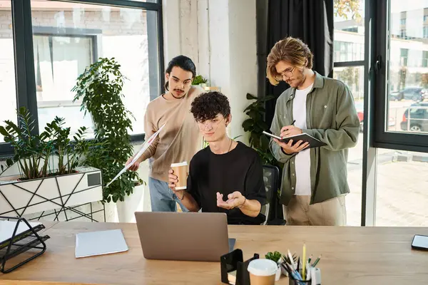 Jeunes entrepreneurs remue-méninges sur un ordinateur portable dans un bureau moderne, trois hommes créant une start-up — Photo de stock