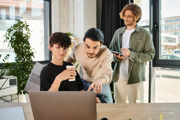 Young man pointing at laptop while explaining his project idea to coworkers in office, startup — Stock Photo