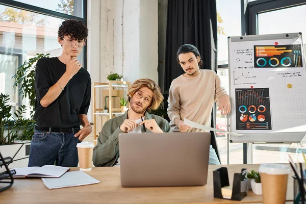 Jungunternehmer in ihren Zwanzigern beim Brainstorming in einem Coworking Space mit Blick auf den Laptop — Stockfoto