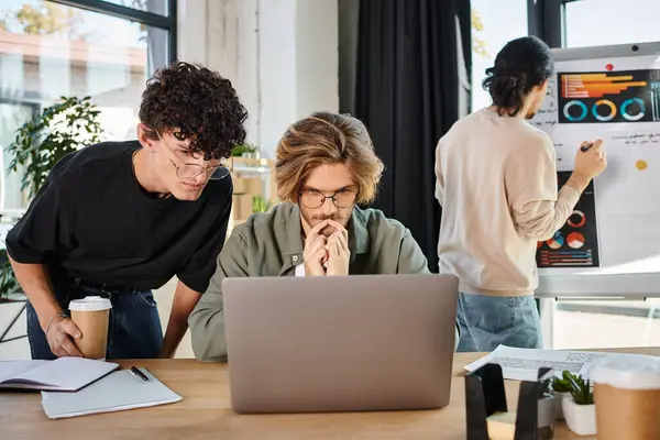Businessmen in their 20s evaluating data on laptop with coworker looking at charts on background — Stock Photo