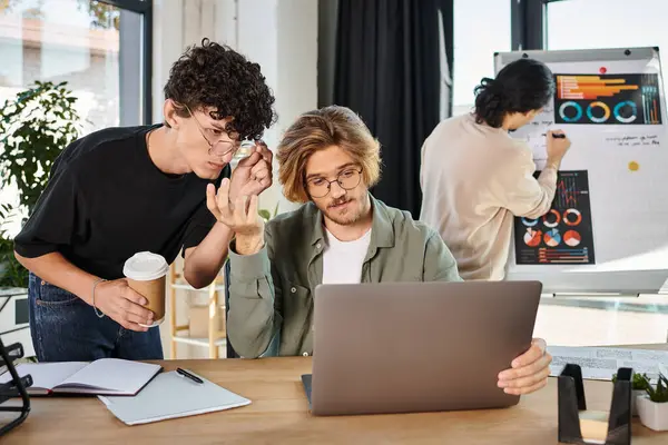 Men in their 20s evaluating data on laptop with coworker looking at charts on background, startup — Stock Photo