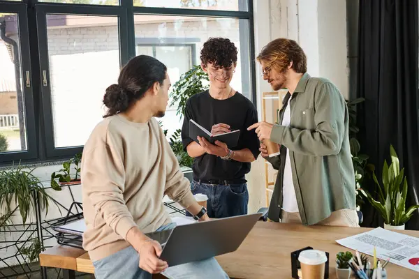 Creative young professional writing his ideas in a notebook near startup team at office, men in 20s — Stock Photo