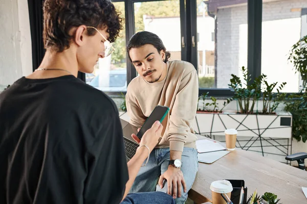 Young professionals with laptop and smartphone in modern office, men in their 20s with gadgets — Stock Photo