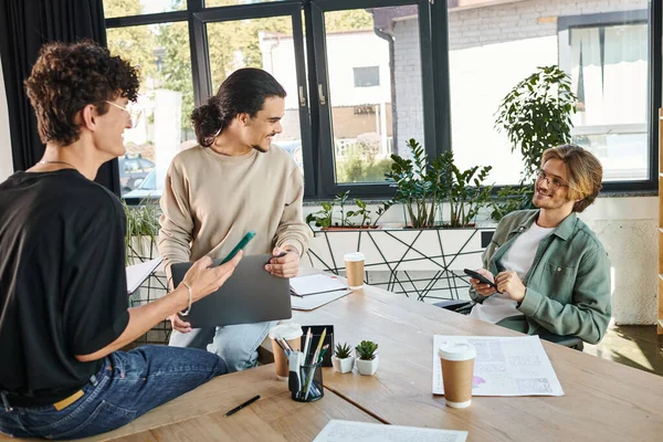 Young startup team members brainstorming with gadgets in modern office space, men in their 20s — Stock Photo